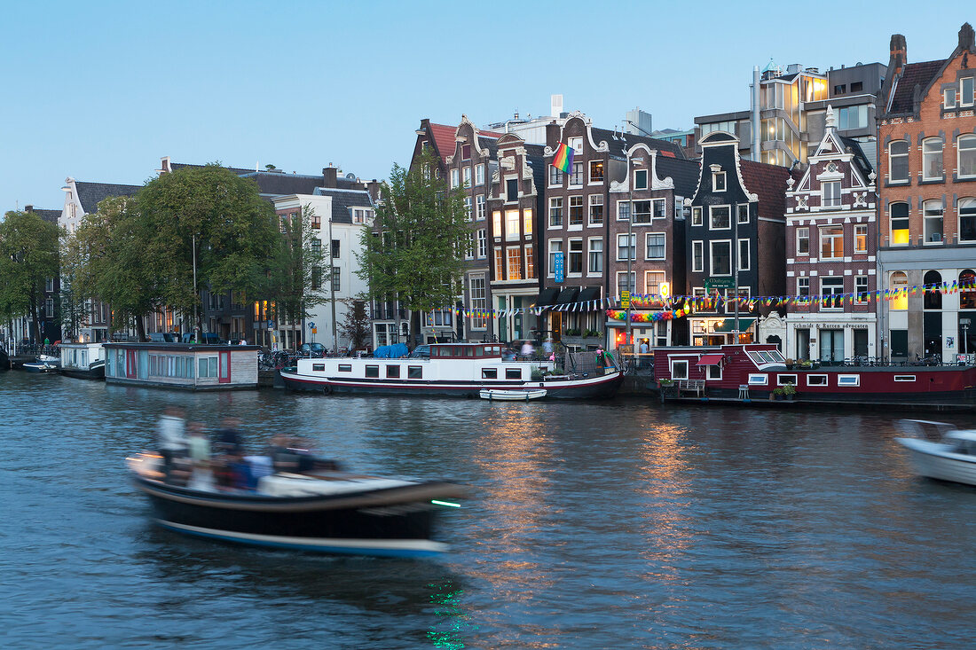 Elevated view of boat, canal and houses in Amstel, Amsterdam, Netherlands, blurred motion