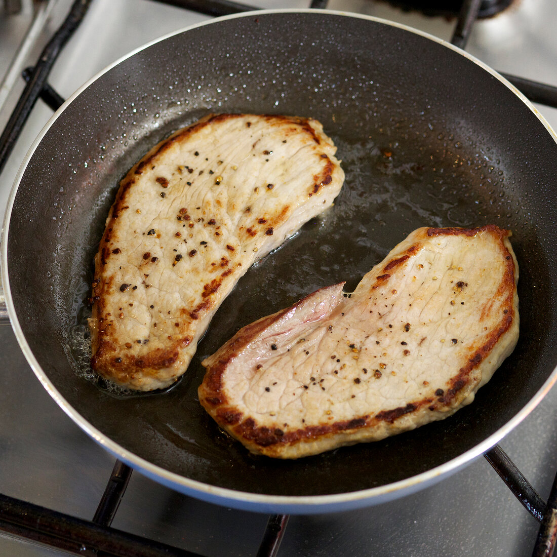 Close-up of schnitzels being fried in pan, step 1