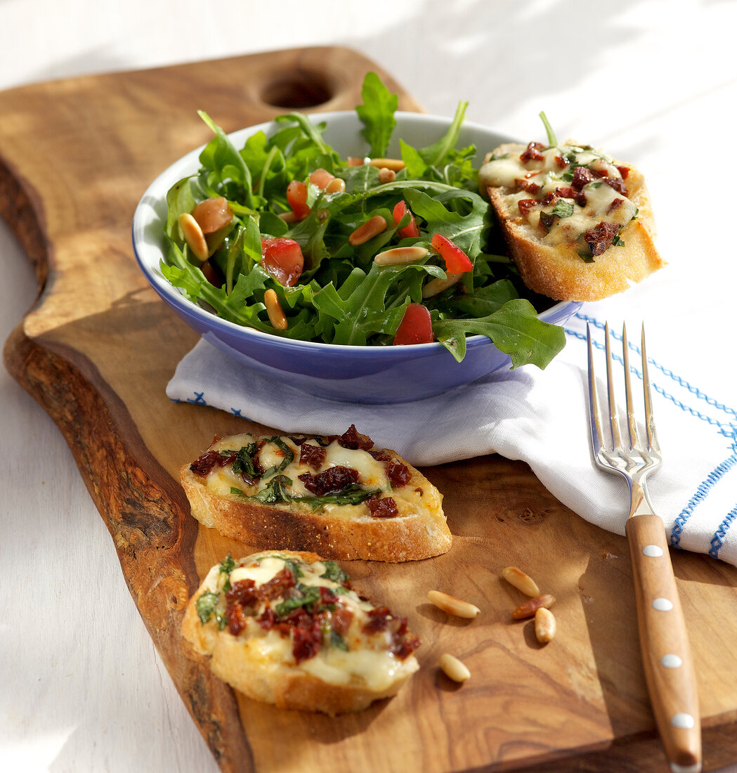 Arugula salad with tomato crostini in bowl