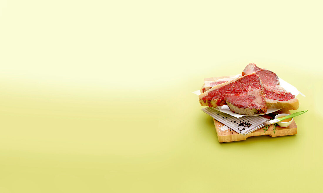 Raw steaks with knife on cutting board