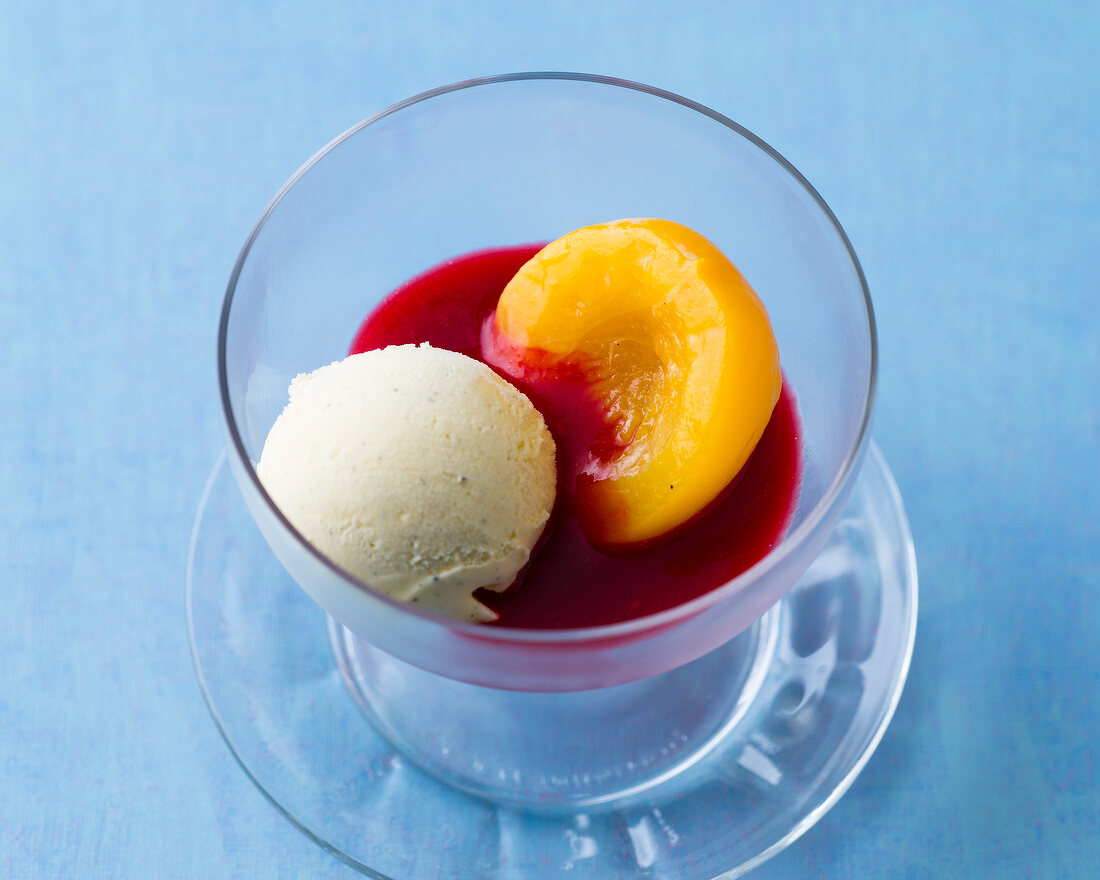 Peach melba in glass bowl on blue background