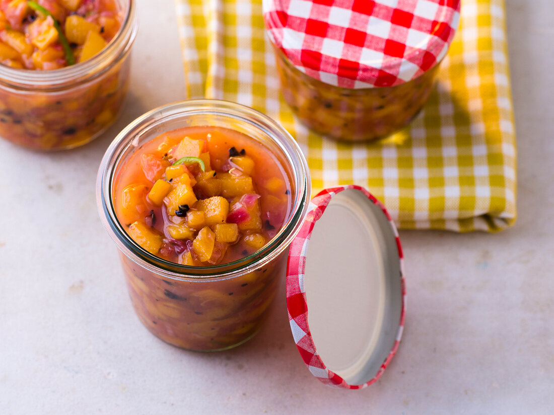 Glass jars of jalapeno peach salsa with coffee
