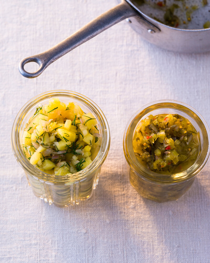 Two glass jar of cucumber relish with ginger and cucumber pineapple salsa