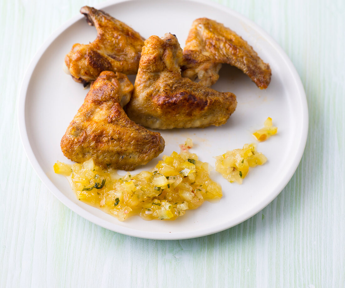Chicken wings grilled with cucumber pineapple salsa on plate