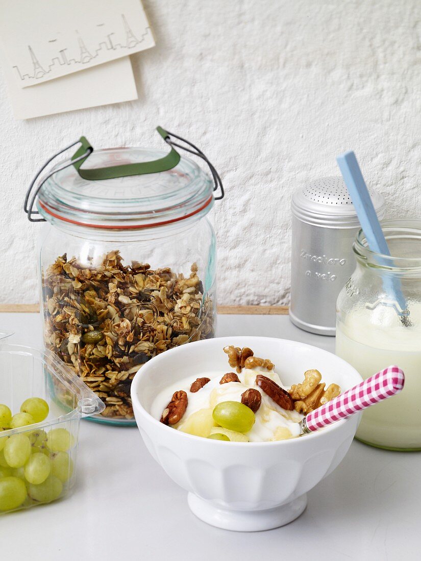 Yogurt with grapes and nuts with a jar of crunchy muesli in the background