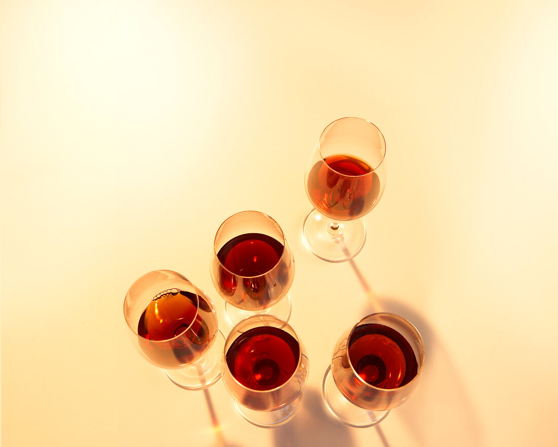 Glasses of red wine on yellow background