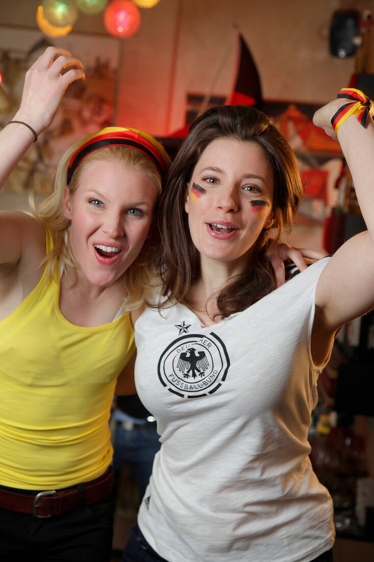 Portrait of two ecstatic women at a football game with Germany flag in background