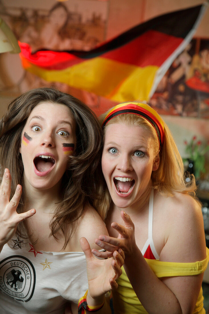 Portrait of two ecstatic women at a football game with Germany flag in background