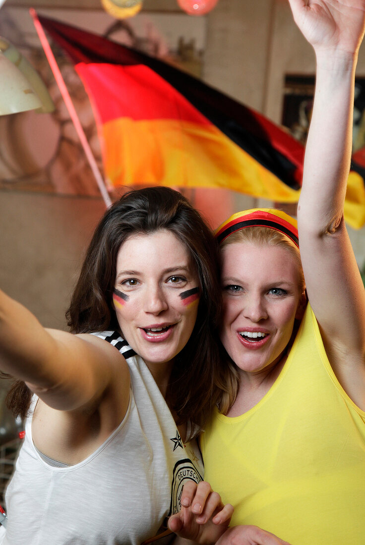 Portrait of two ecstatic women at a football game with Germany flag in background