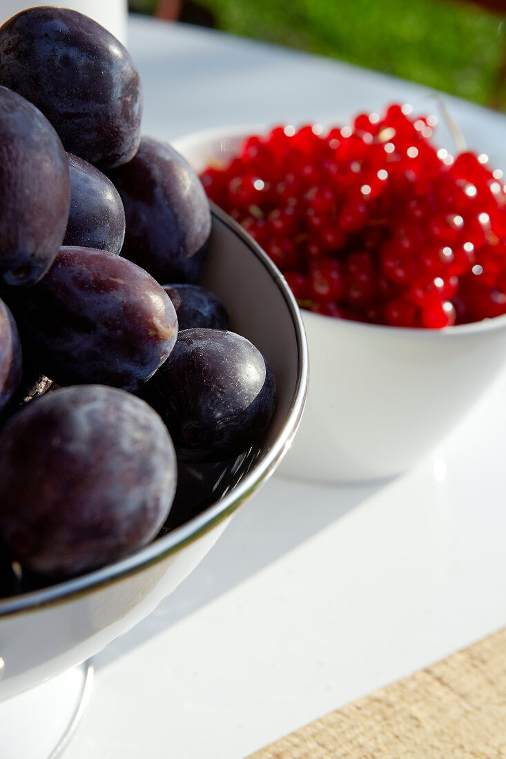 Close-up of two bowl of plums and red currants