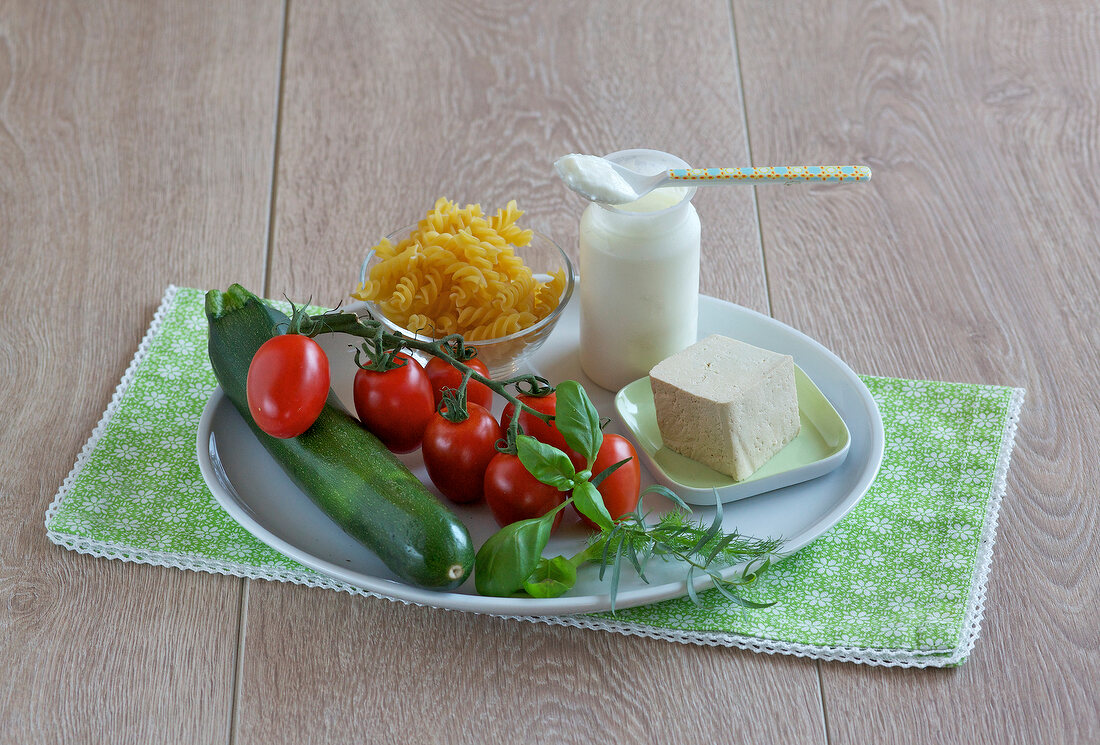 Zucchini, tomatoes, tofu, yogurt and pasta in serving dish