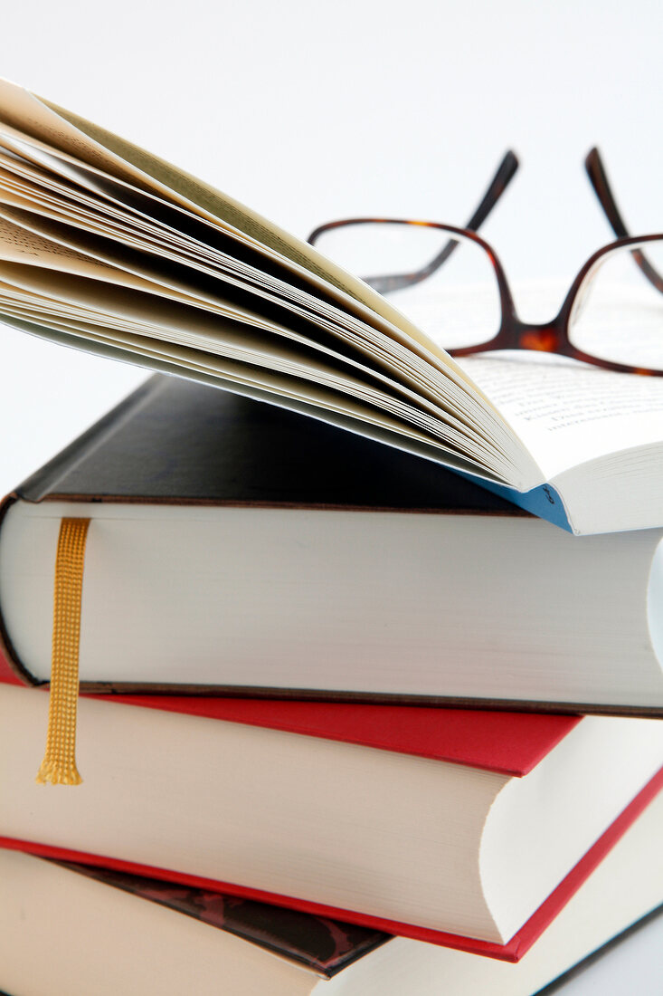 Close-up of stack of books with spectacles on it