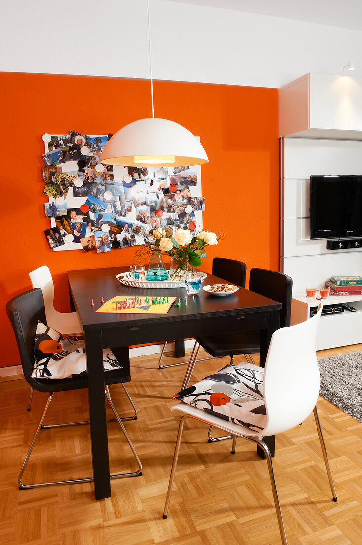 Dining room with dining table, chairs, pictures, magnetic board on orange wall
