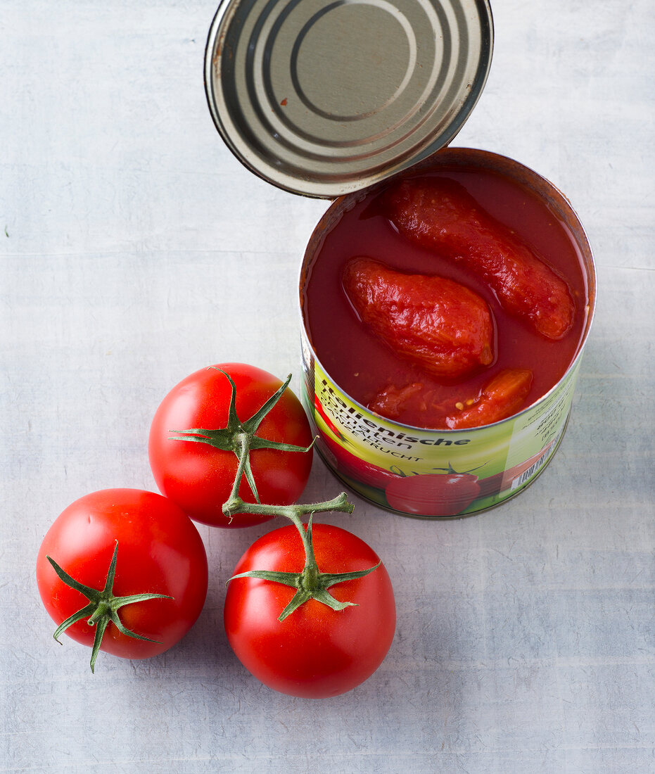 Three whole tomatoes besides tomato sauce in tin