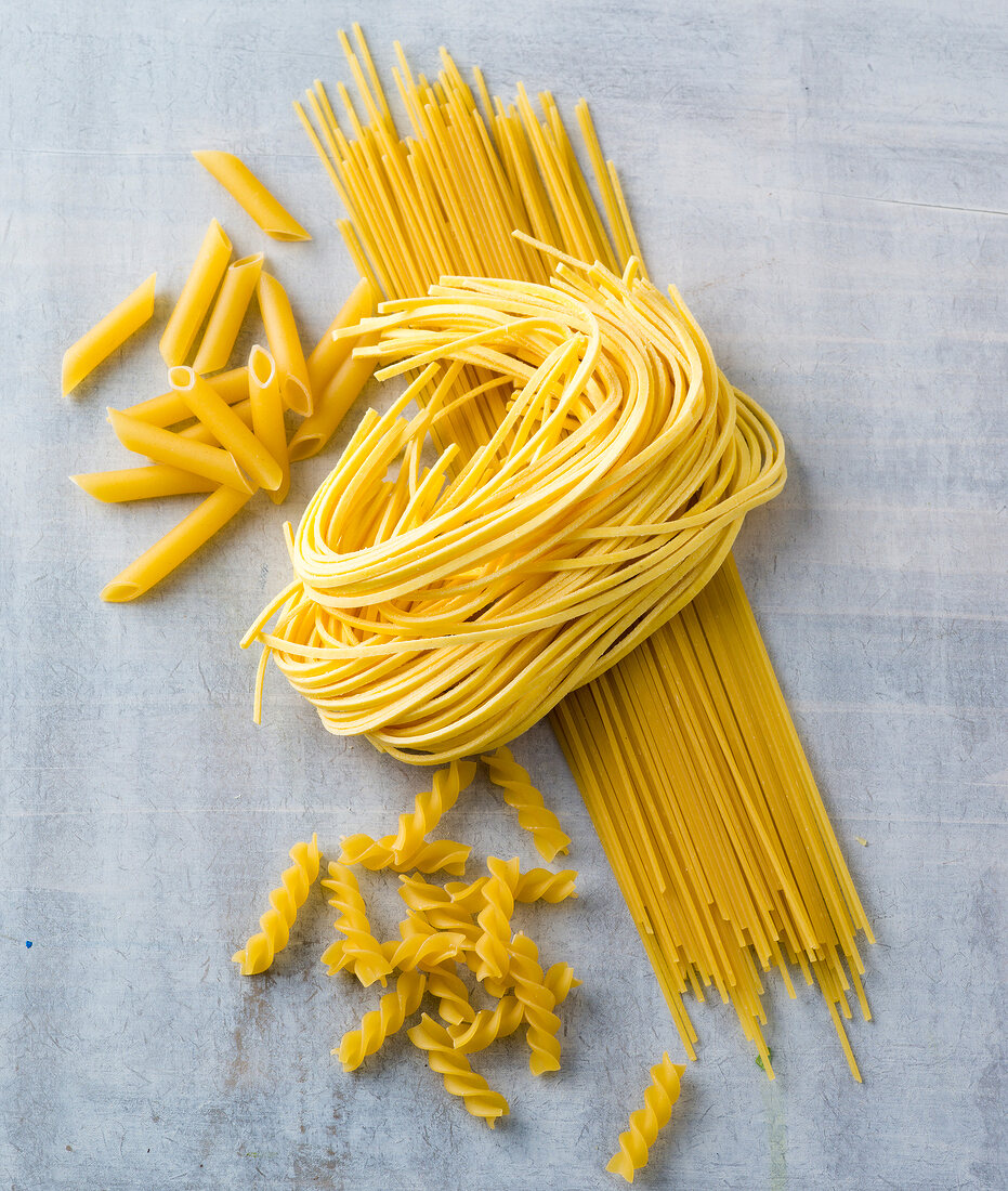 Various shaped durum wheat pasta on gray background