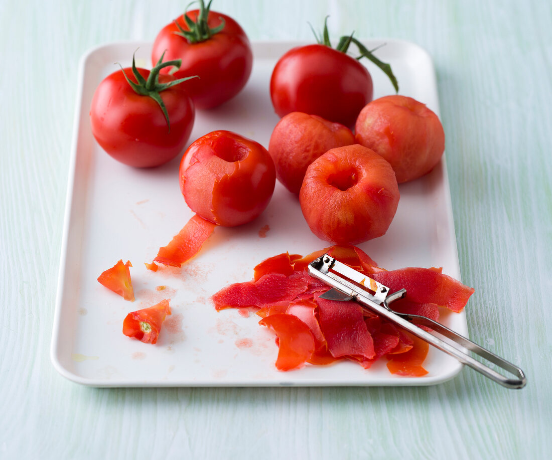Tomatoes being peeled by peeler for preparing vegetarian Italian sauce, step 1