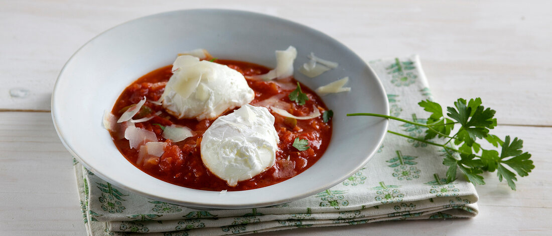 Poached eggs with devil sauce in bowl