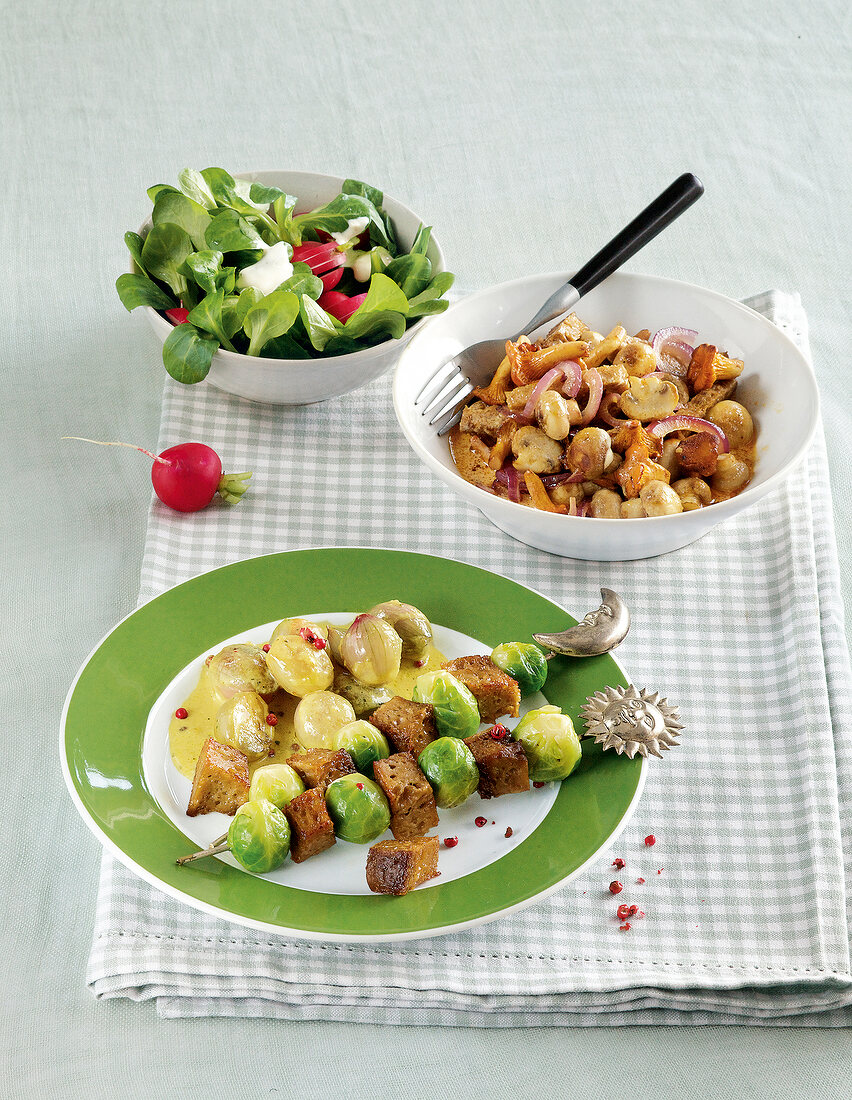 Brussels sprouts seitan skewers on plate with sliced ??seitan in bowl