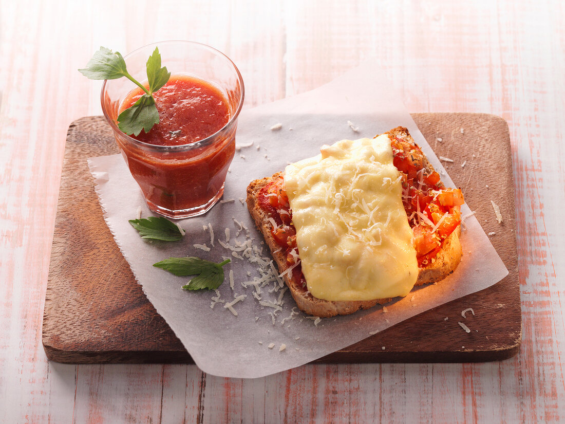 Tomato sauce in glass and whole meal sandwich on chopping board
