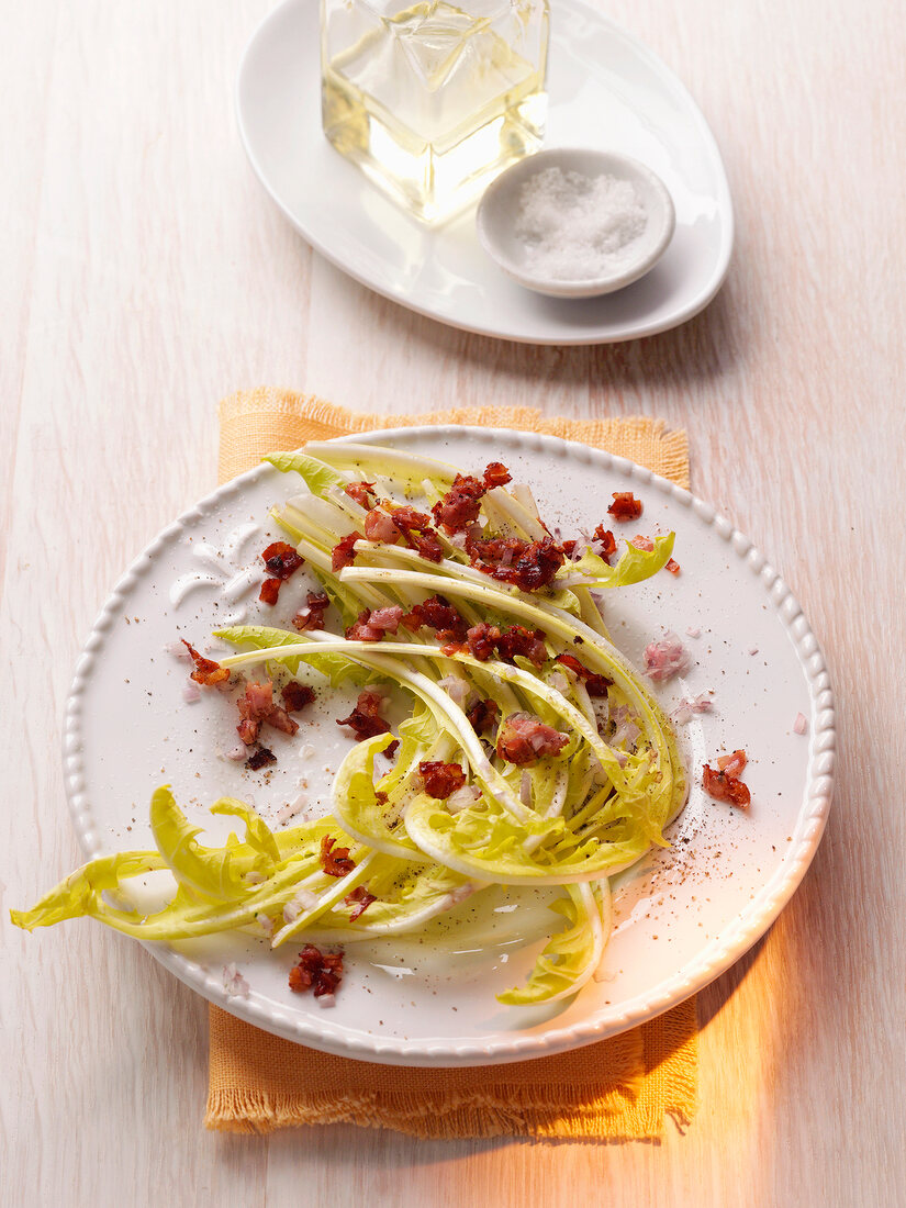Dandelion salad with bacon in serving dish