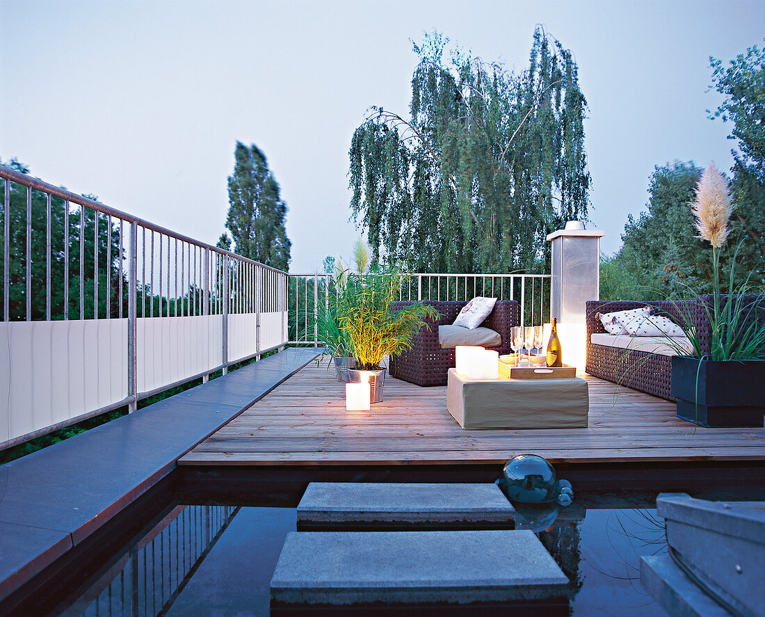 Dachterrasse mit Teich, Holzdielen und Sitzecke, abends, blaue Stunde