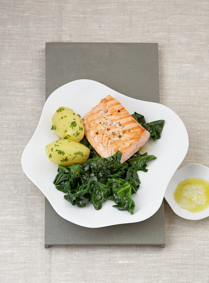 Salmon steak with spinach and potato on plate