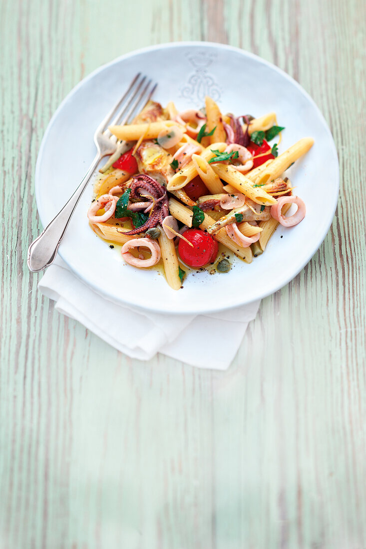 Penne pasta with roasted artichokes and squid on plate