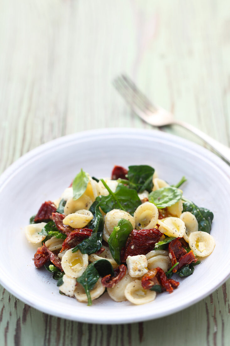 Orecchiette pasta with feta cheese, spinach and tomatoes on plate
