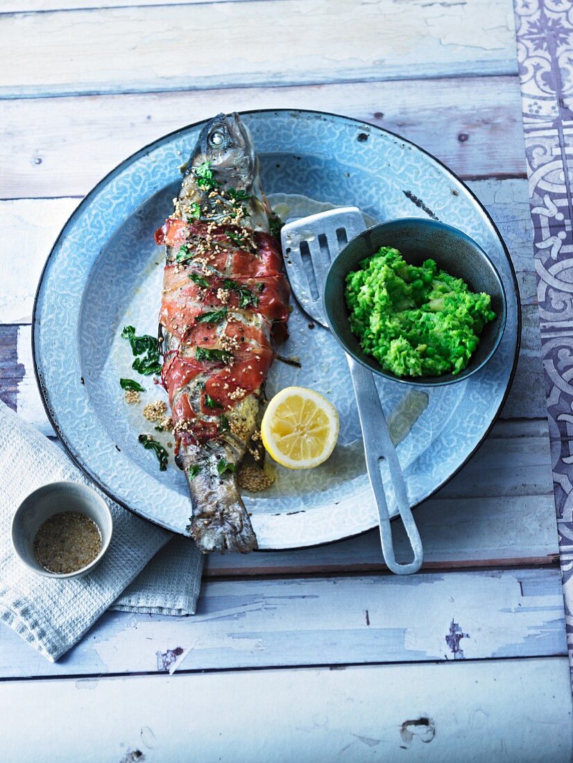 Stuffed trout wrapped in ham with sesame seed butter and mushy peas and parsnips