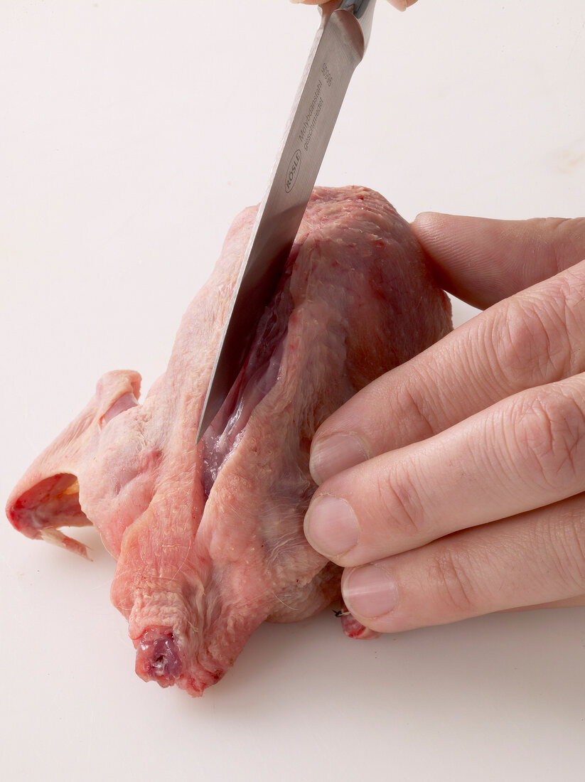 Rib bones of quail being removed with knife, step 1