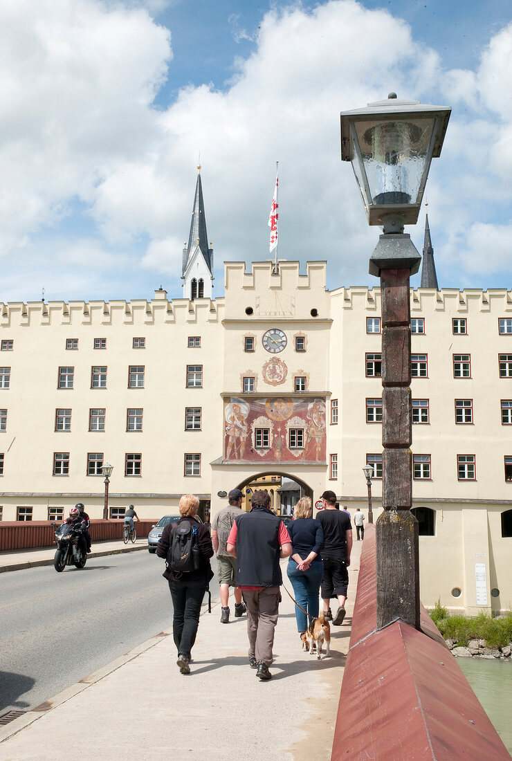 Woman walking on street in front of Wasserburg am Inn in Rosenheim, Bavaria, Germany