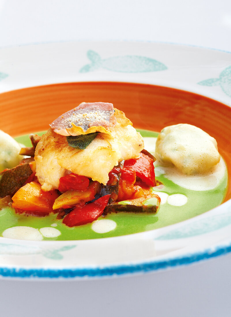 Close-up of saltimbocca on ratatouille with vegetables and herb foam on plate