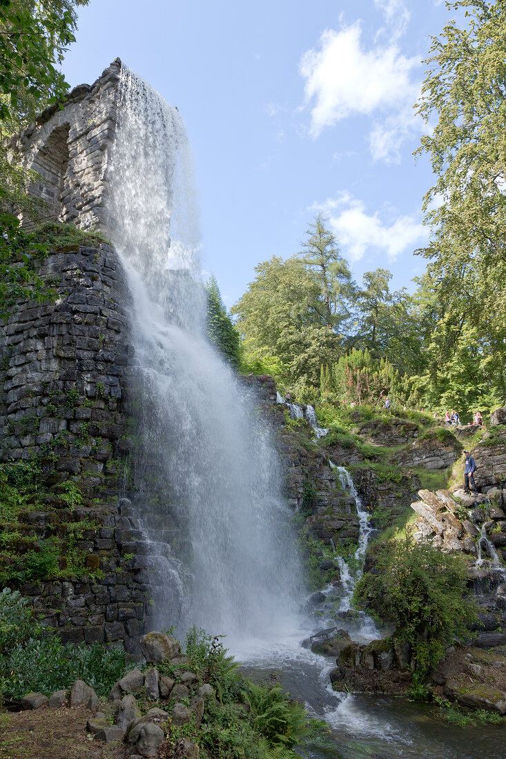 Water falling from aqueduct with tress around at Bergpark Wilhelmshohe, Hesse, Germany