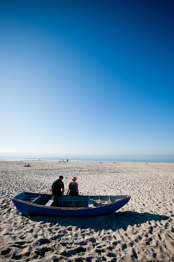 Two people sitting in boat at beach near Kampen, Sylt, Germany