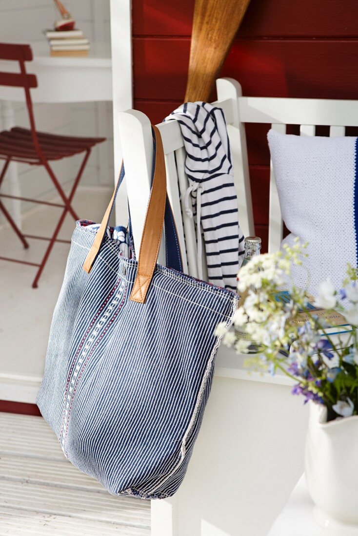 A summer bag a a border of stars hanging on the end of a bench