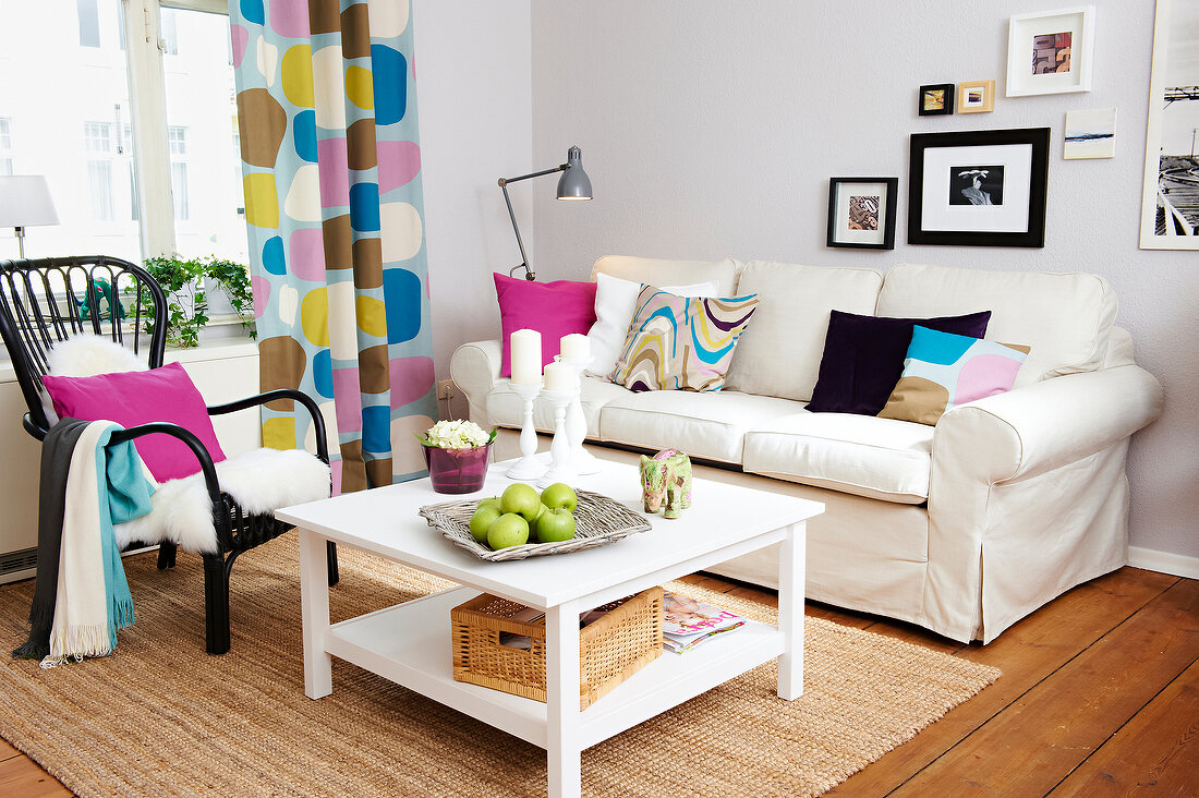 Living room in pastel tones with sofa, rattan mat, chair and table