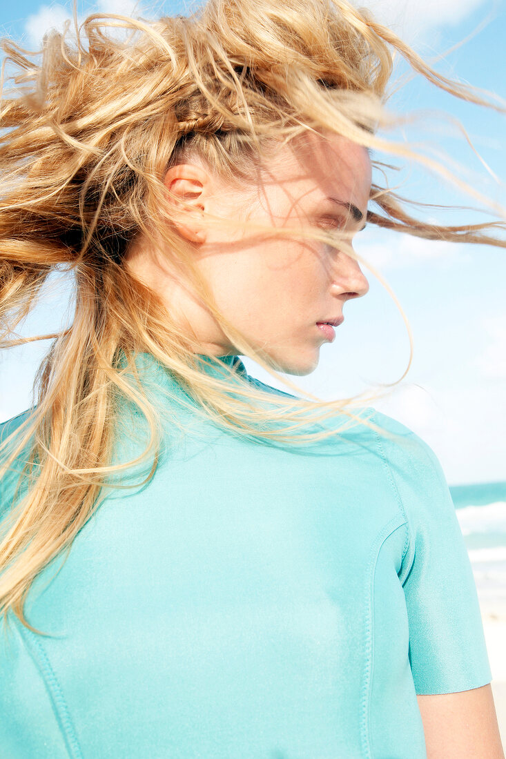 Woman in a green wetsuit with wind-disheveled hair