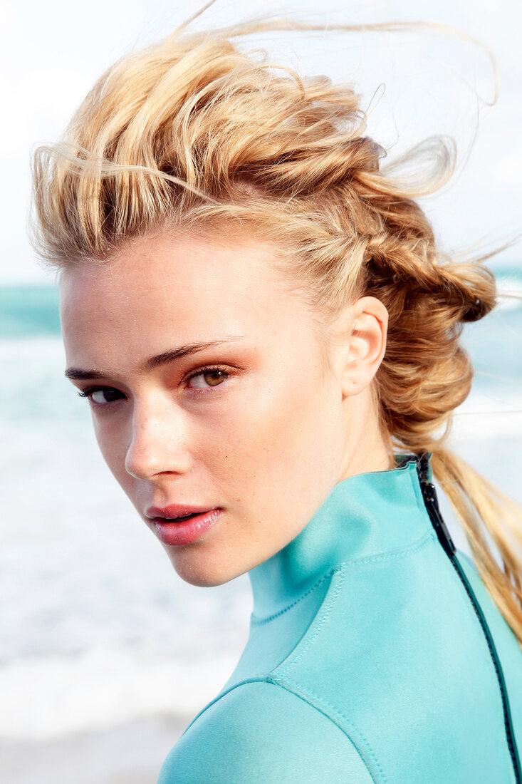 Blonde woman with long, braided hair in a green diving suit