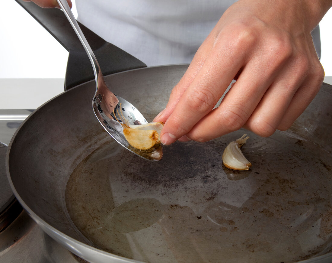 Garlic cloves being fried in pan