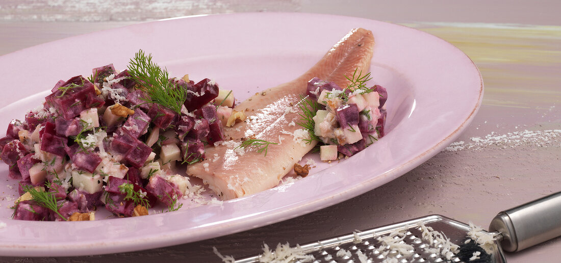 Close-up of beetroot salad with fish on serving plate