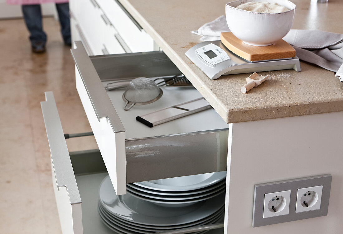 Close-up of glossy drawers with plates and kitchen utensils