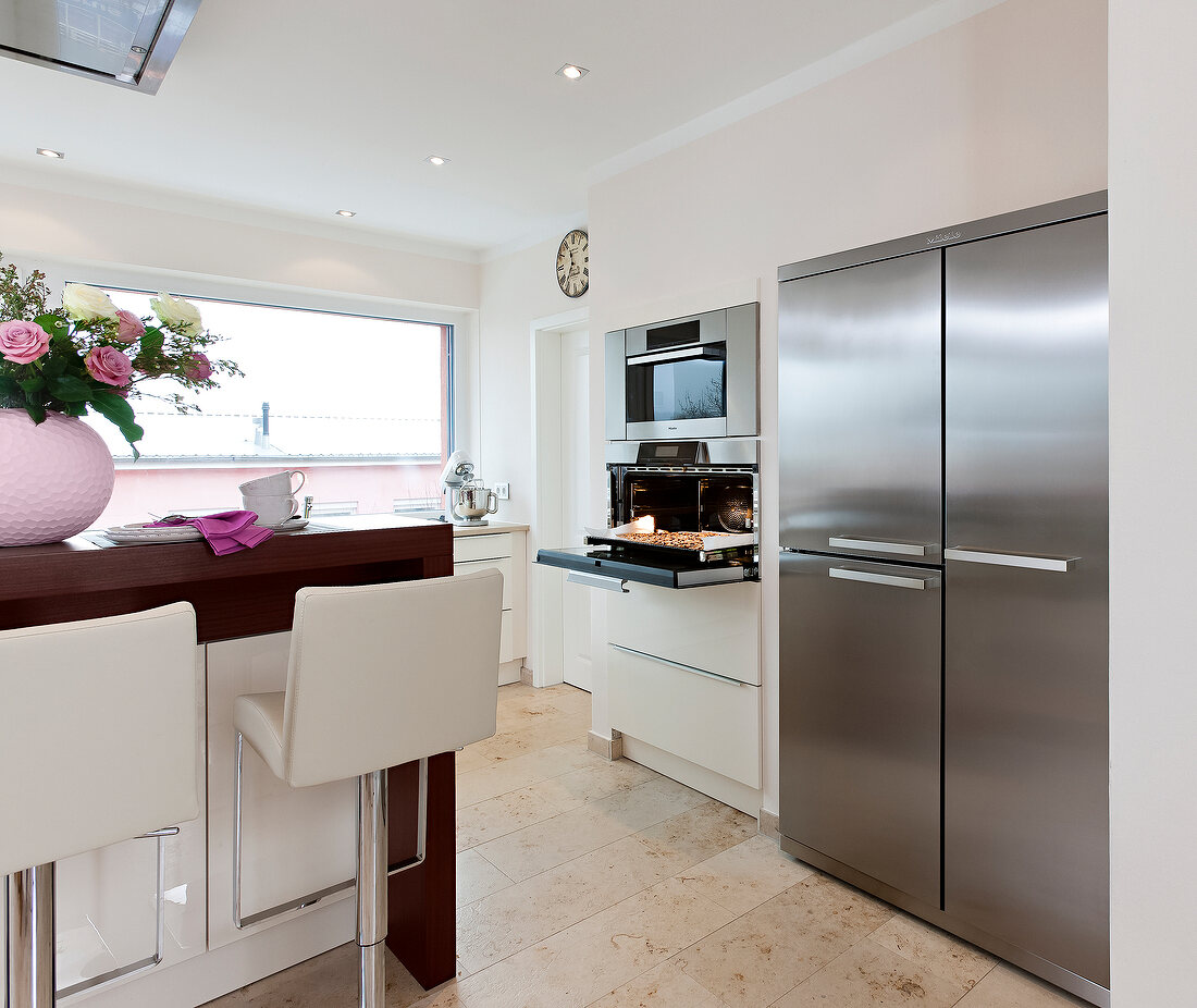 View of kitchen with breakfast bar with high chairs in front of oven and refrigerator