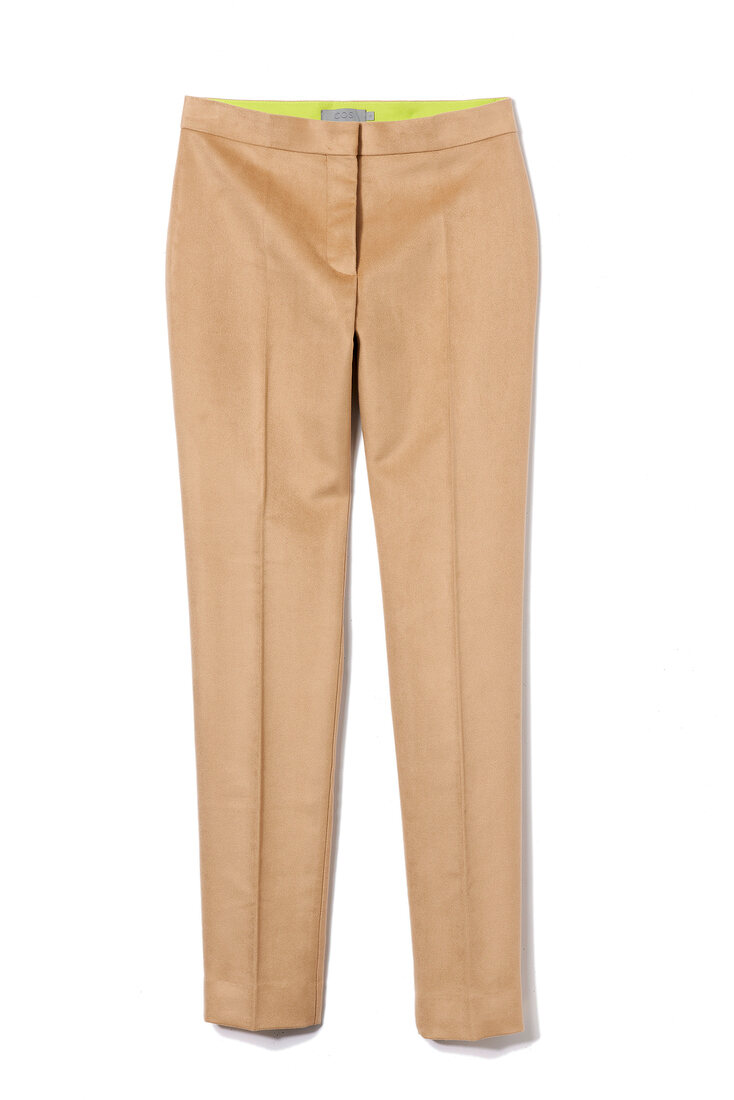 Close-up of beige narrow cut crease trousers on white background