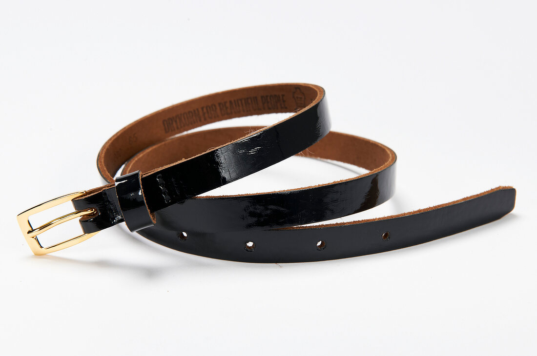 Close-up of black narrow leather belt on white background