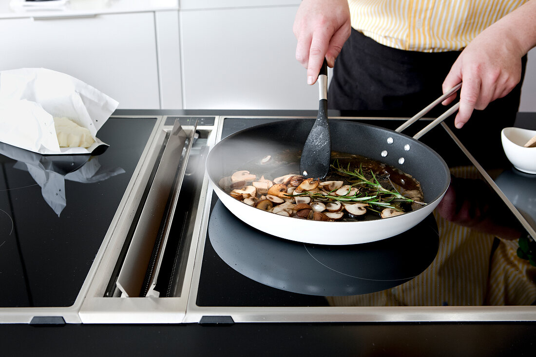 Man's hands stir frying mushroom in frying pan