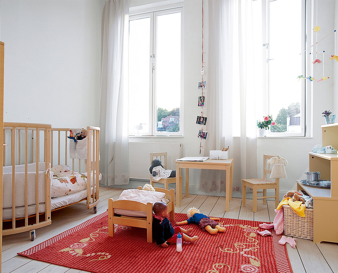 Blick in ein helles Kinderzimmer mit Puppen und Sitzplatz
