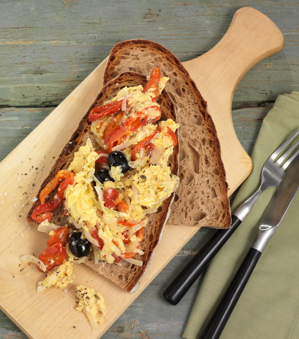 Peppers, onion, scrambled eggs and olives on bread
