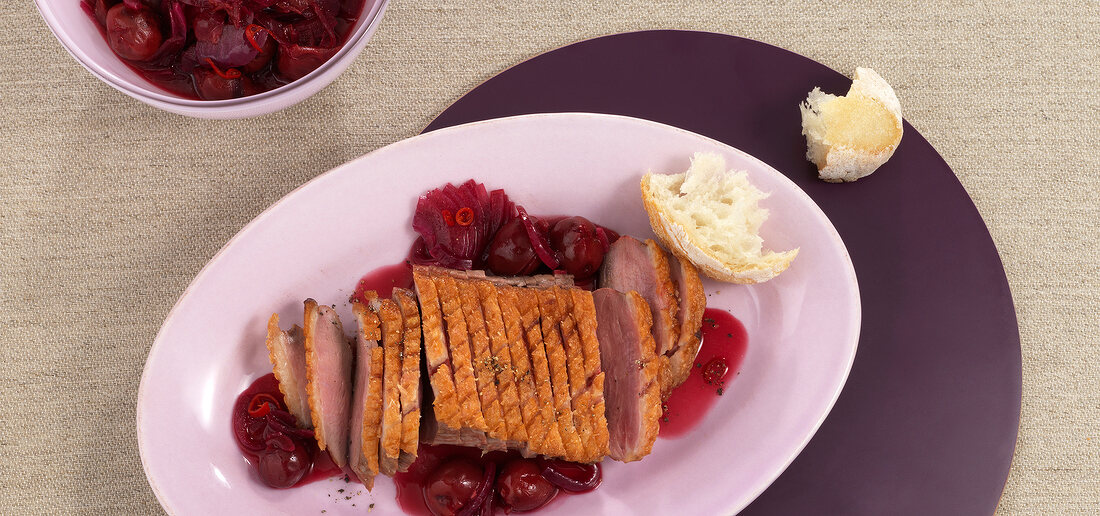 Duck breast with chilli cherries on plate