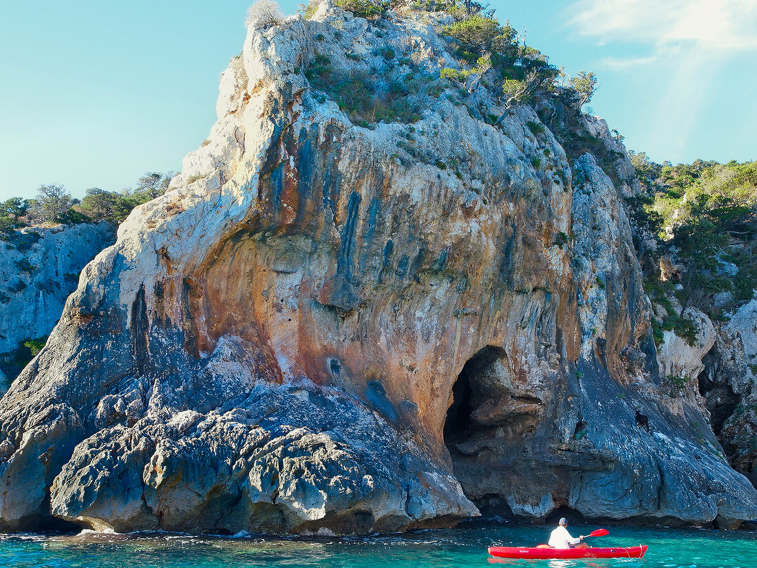 Person kayaking at Grotto in Gulf of Orosei, Sardinia, Italy