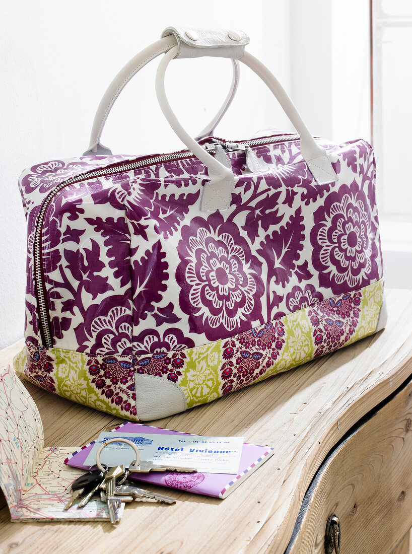 Close-up of flowered Weekender bag with keys and envelopes on table